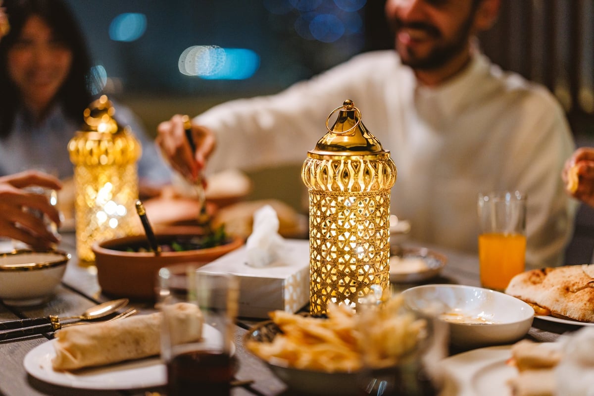 Middle Eastern young adults enjoying a Ramadan dinner together featuring intricate Fanous on the table creating a warm atmosphere