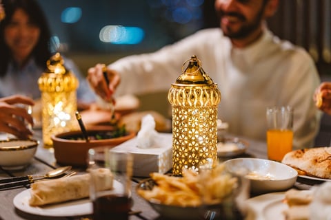 Middle Eastern young adults enjoying a Ramadan dinner together featuring intricate Fanous on the table