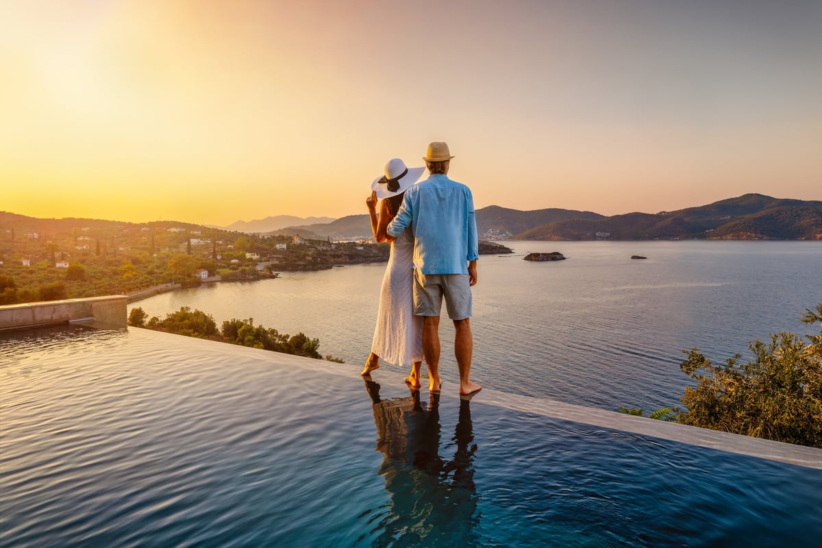 Romantic couple summer vacation standing by swimming pool enjoys beautiful sunset
